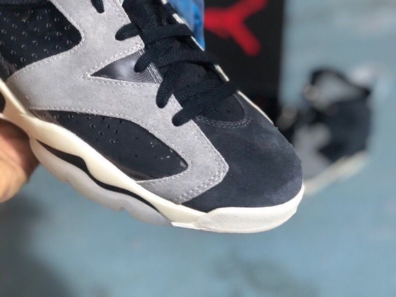 Close-up of the toe area showing black laces, a light grey overlay, perforated black paneling, and a rounded white toe edge.