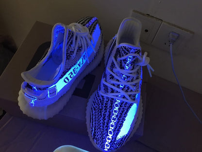 The sneakers shown under blue light, highlighting illuminated details on the uppers and soles.
