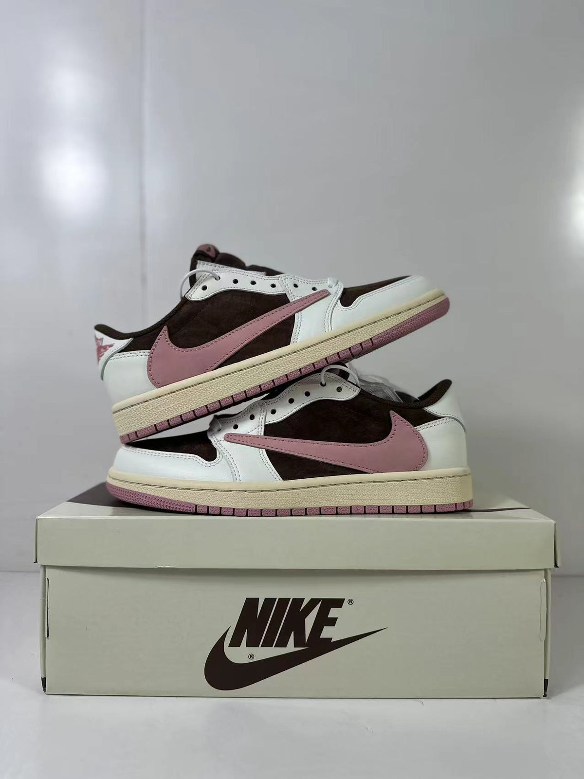 Two sneakers arranged together to show their side profiles and pink outsole edges.