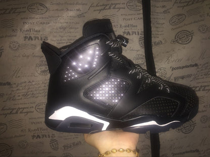 Side profile of a black high-top sneaker showing perforated panels, layered construction, and white midsole accents.