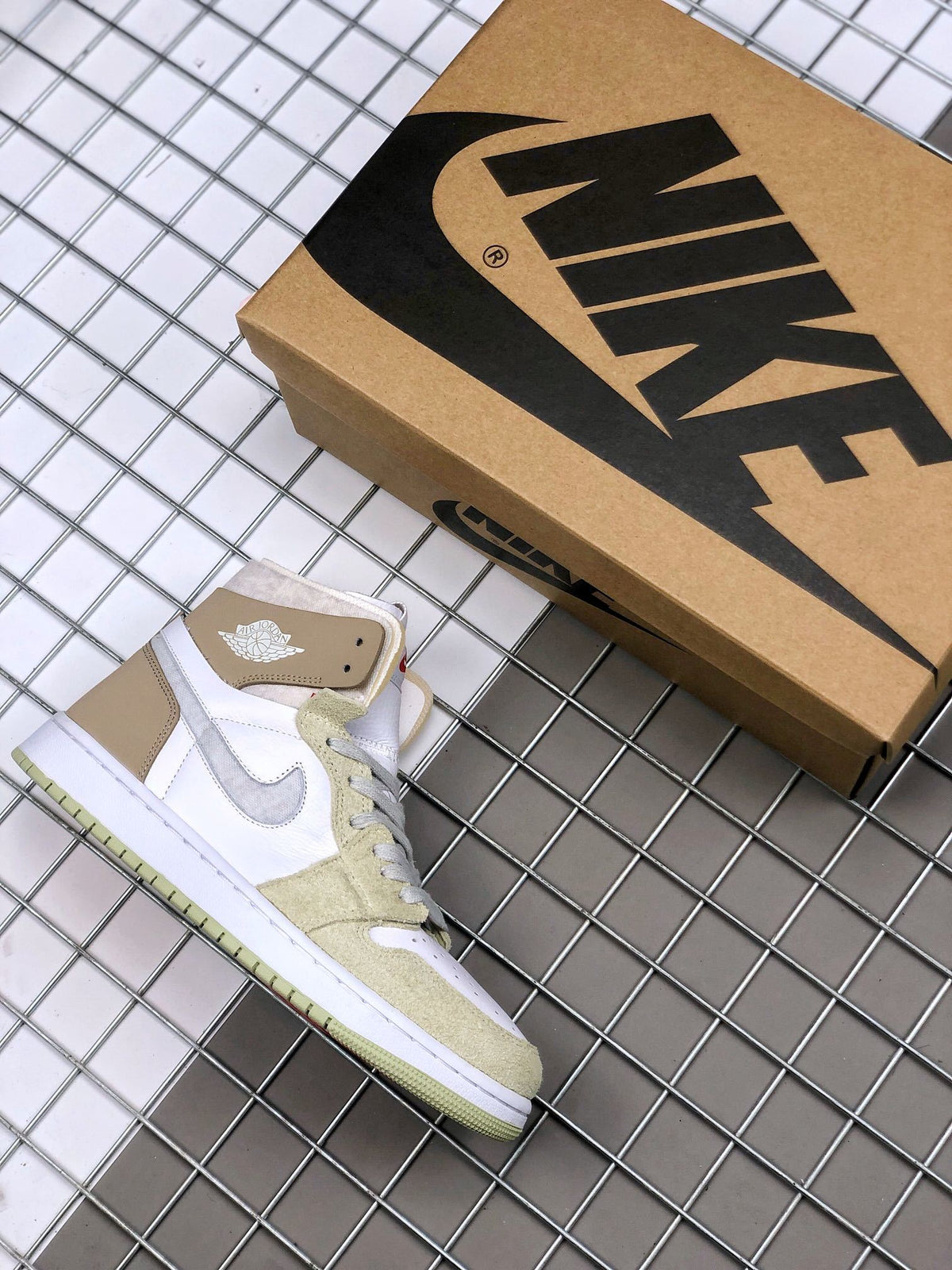 Air Jordan 1 Zoom CMFT sneaker beside a Jordan shoebox, showing the white, olive green, and brown color combination.