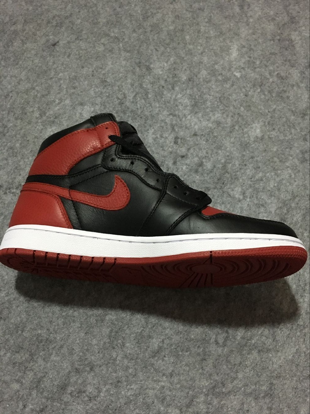 Side profile showing the high-top silhouette, red Swoosh, black panels, white midsole, and red outsole.