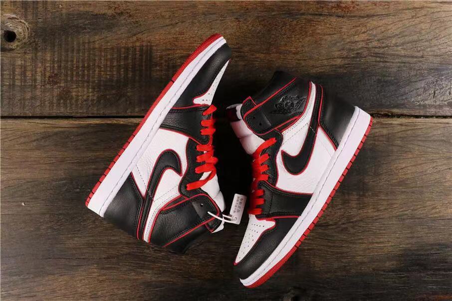 Pair of black, white, and red high-top sneakers arranged on a wooden surface.