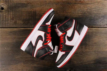 Pair of black, white, and red high-top sneakers arranged on a wooden surface.