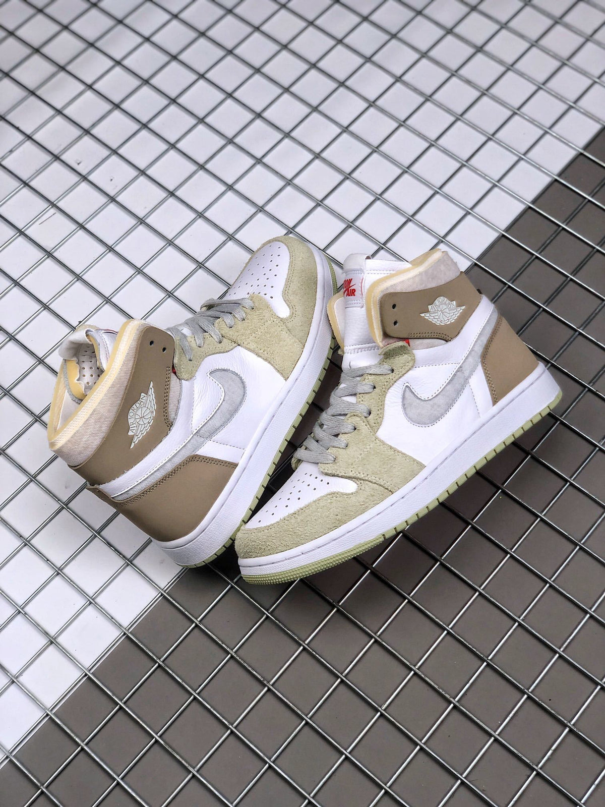 Pair of Jordan high-top sneakers viewed from above, showing the olive green overlays, white perforated toe boxes, and brown ankle panels.