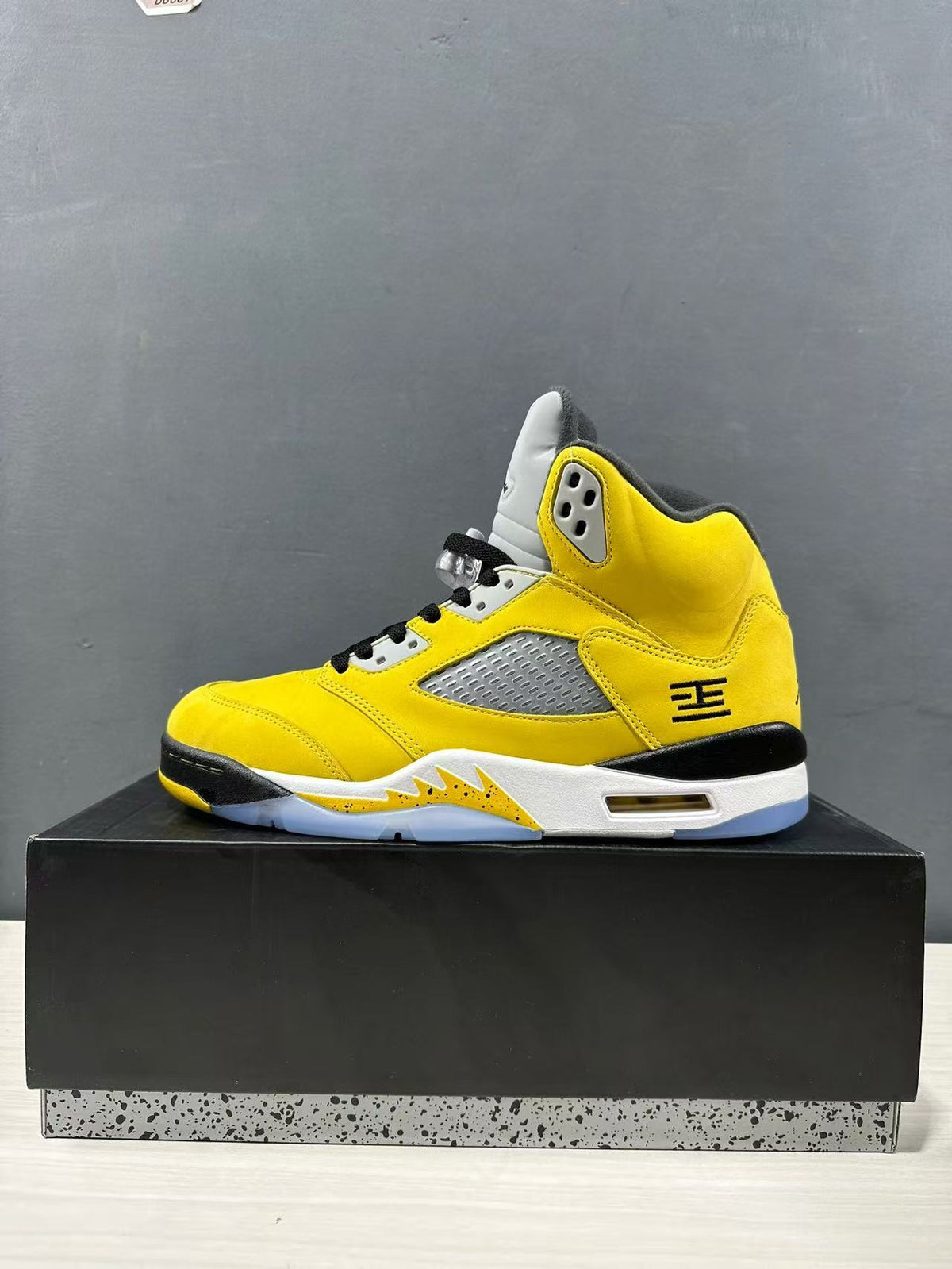 Side profile of a yellow mid-top sneaker with gray mesh panel, black accents, and translucent outsole.
