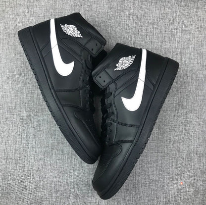 Two black and white mid-top sneakers arranged diagonally to show their side profiles and toe boxes.