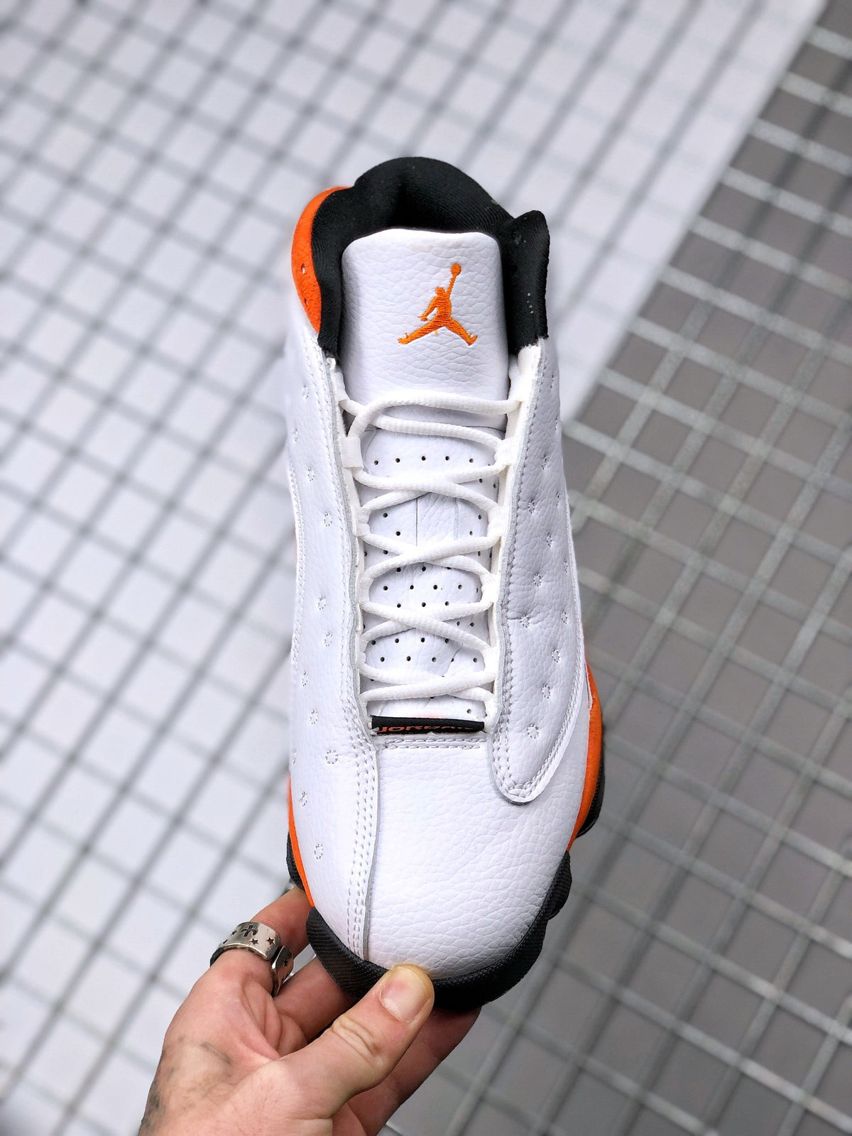 Front view showing the laces, tongue, and orange logo on a white Air Jordan 13