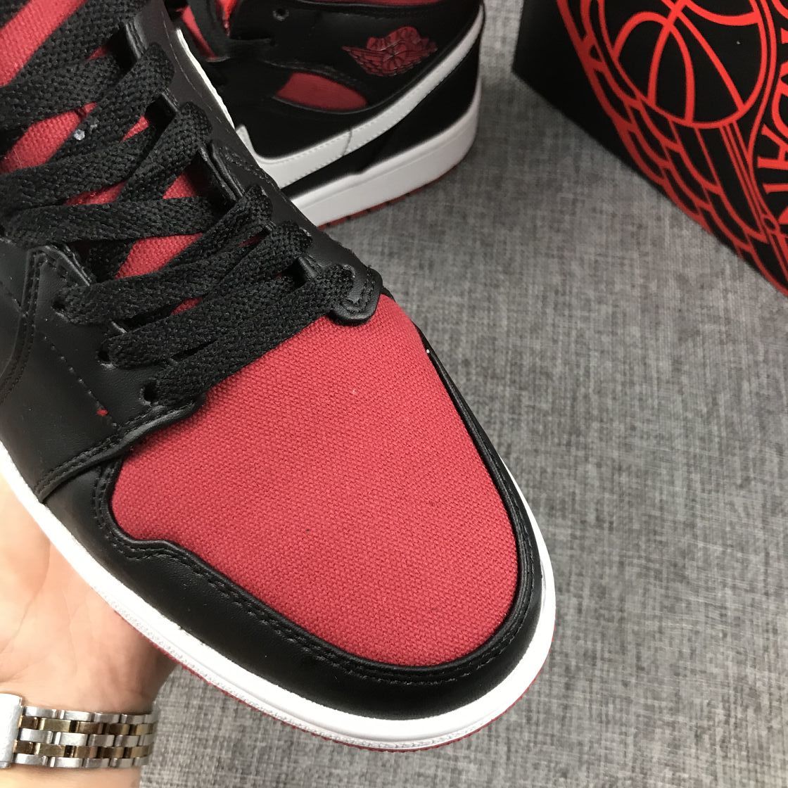 Close-up of the red textile-looking toe panel, black laces, and black-and-white trim.