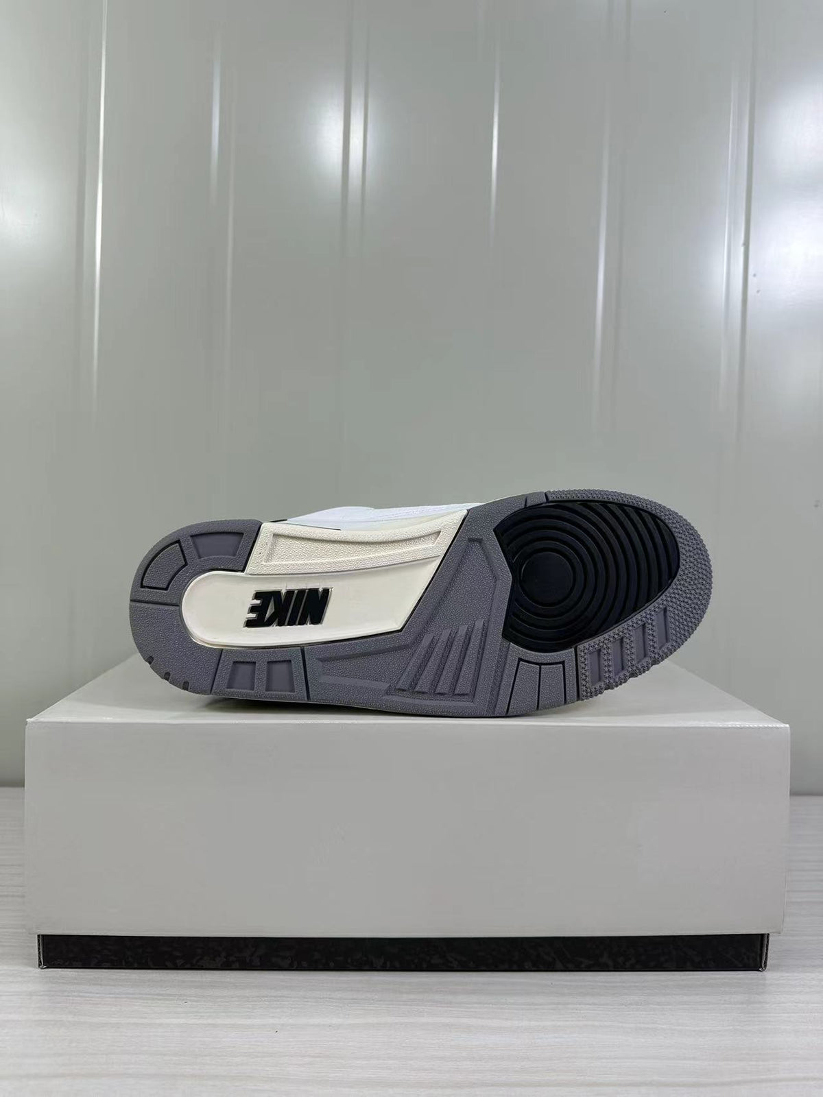 Outsole view showing a gray rubber tread with black circular traction detail and a white inset panel.