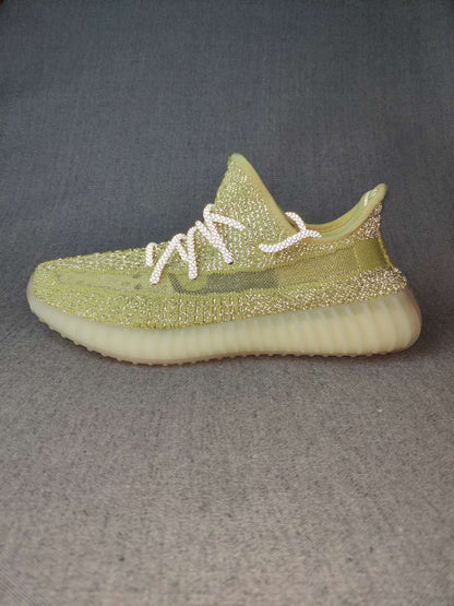 Side profile of a green low-top sneaker with a dark side stripe, white laces, and light cream sole.