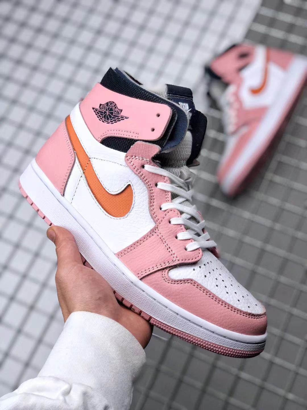 Angled front-side view showing the perforated toe box, white laces, pink overlays, and orange side accent.