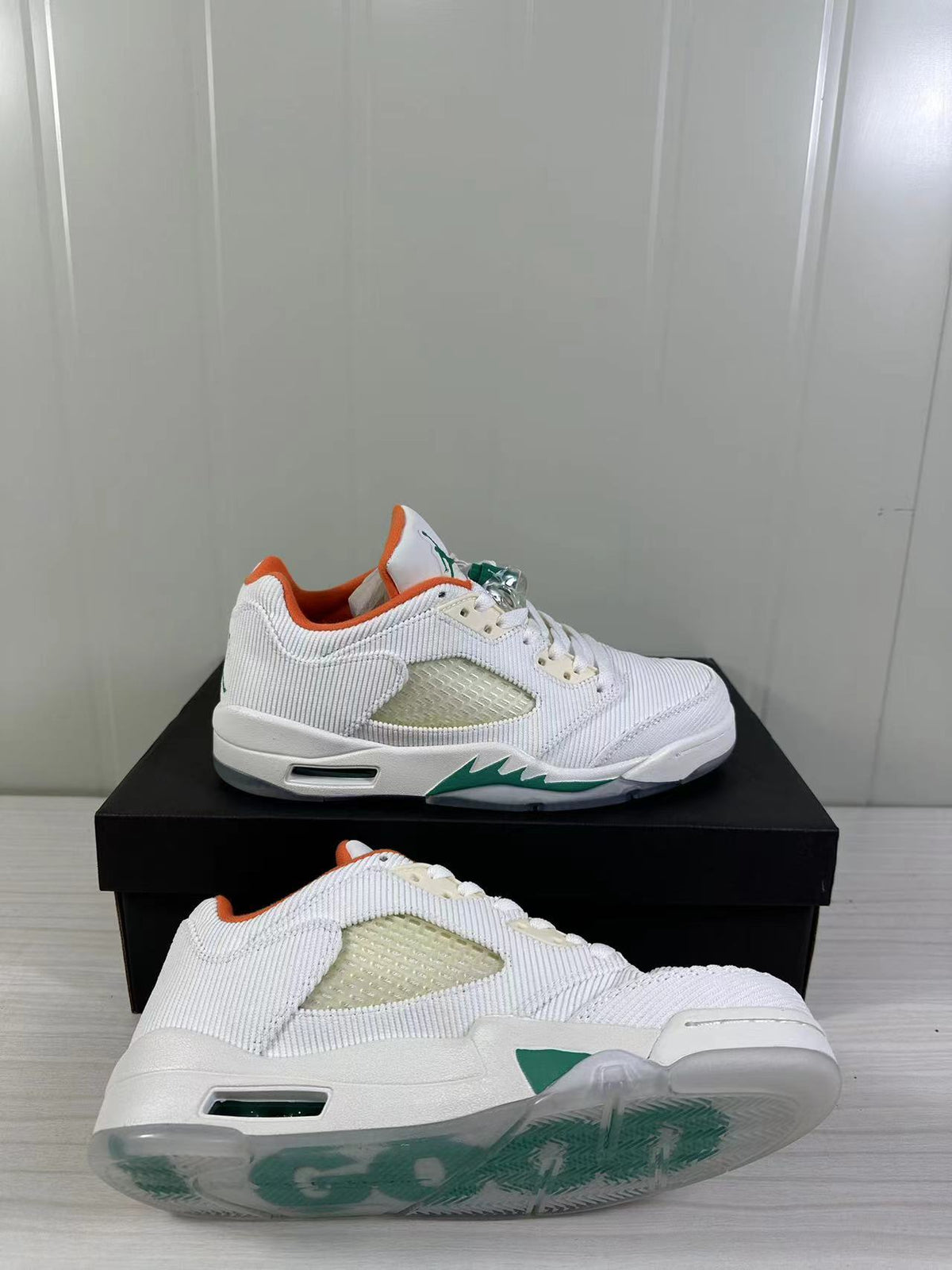 Angled view of the white and green sneaker pair, including the translucent outsole and mesh-style upper.