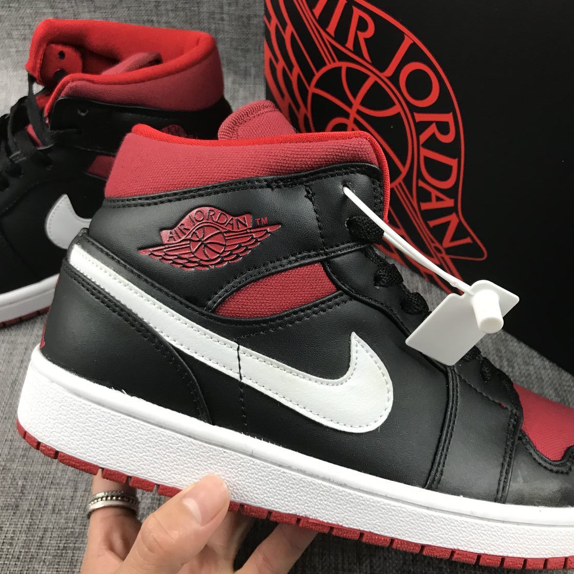Close-up side view showing the Jordan wing emblem, white Swoosh, red collar, and white midsole.