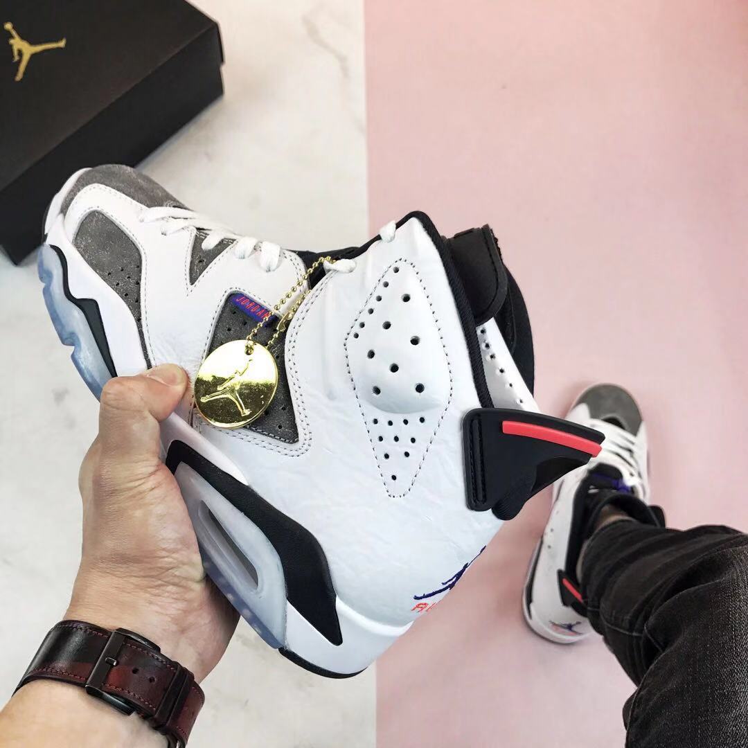 Side view showing the white and grey upper, perforated panels, black midsole accents, translucent outsole, and gold shoe charm.
