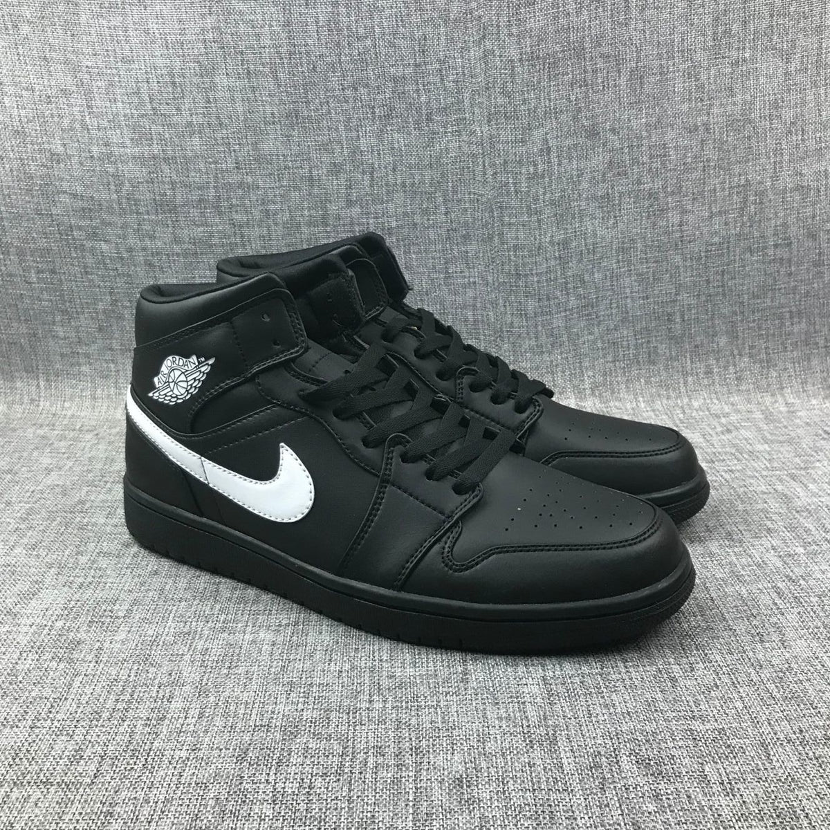Three-quarter front view of the black and white mid-top sneaker pair.