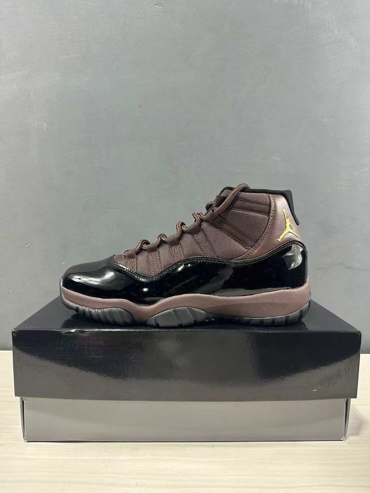 Side profile of a black and bronze Air Jordan 11 Retro high-top sneaker.