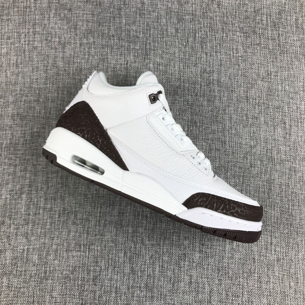 Angled view of the white and brown Jordan Air Jordan 3 sneaker showing the textured overlays and heel air unit.
