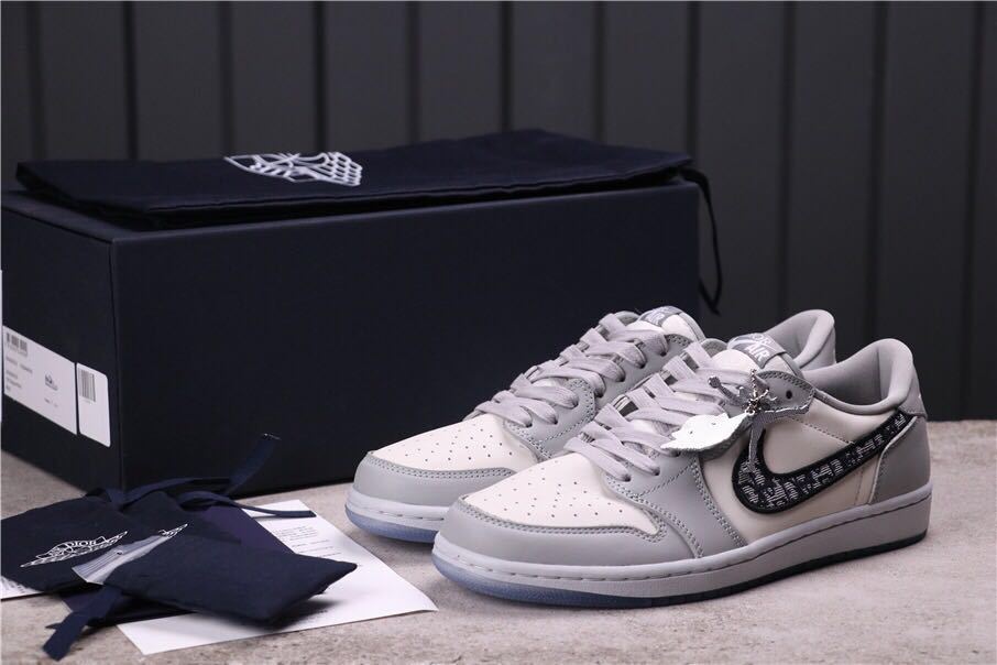 Pair of grey and white low-top sneakers displayed with a black box and accessory packaging.