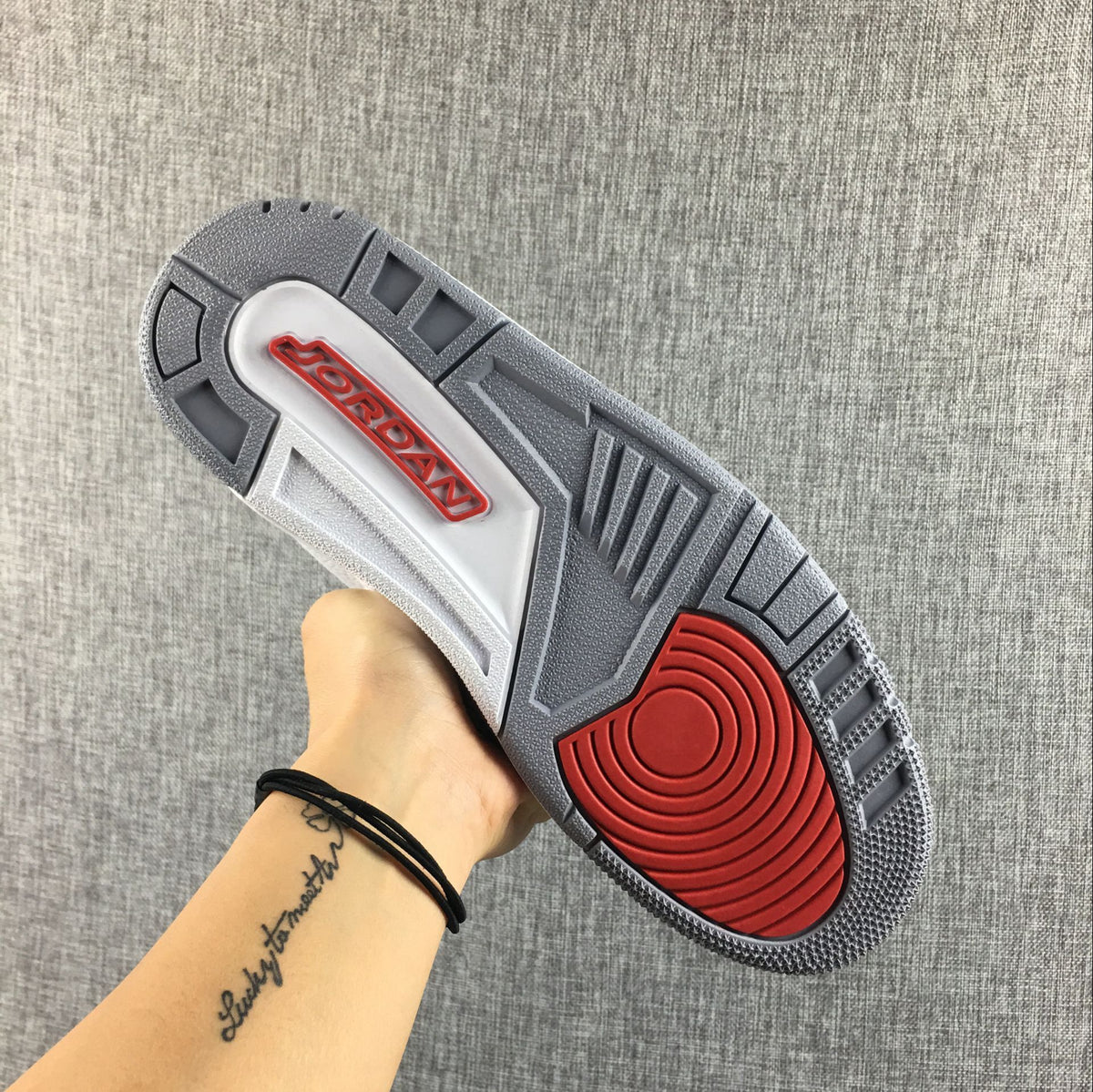Underside of the sneaker showing a grey and red patterned outsole