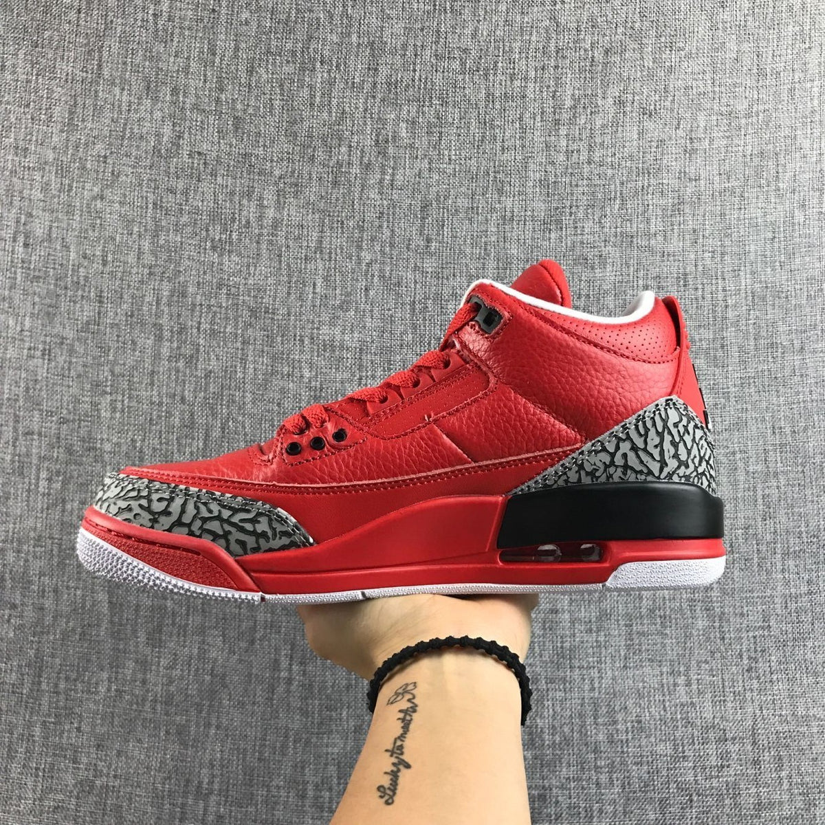 Side profile of the red sneaker with black heel accent and visible heel unit.