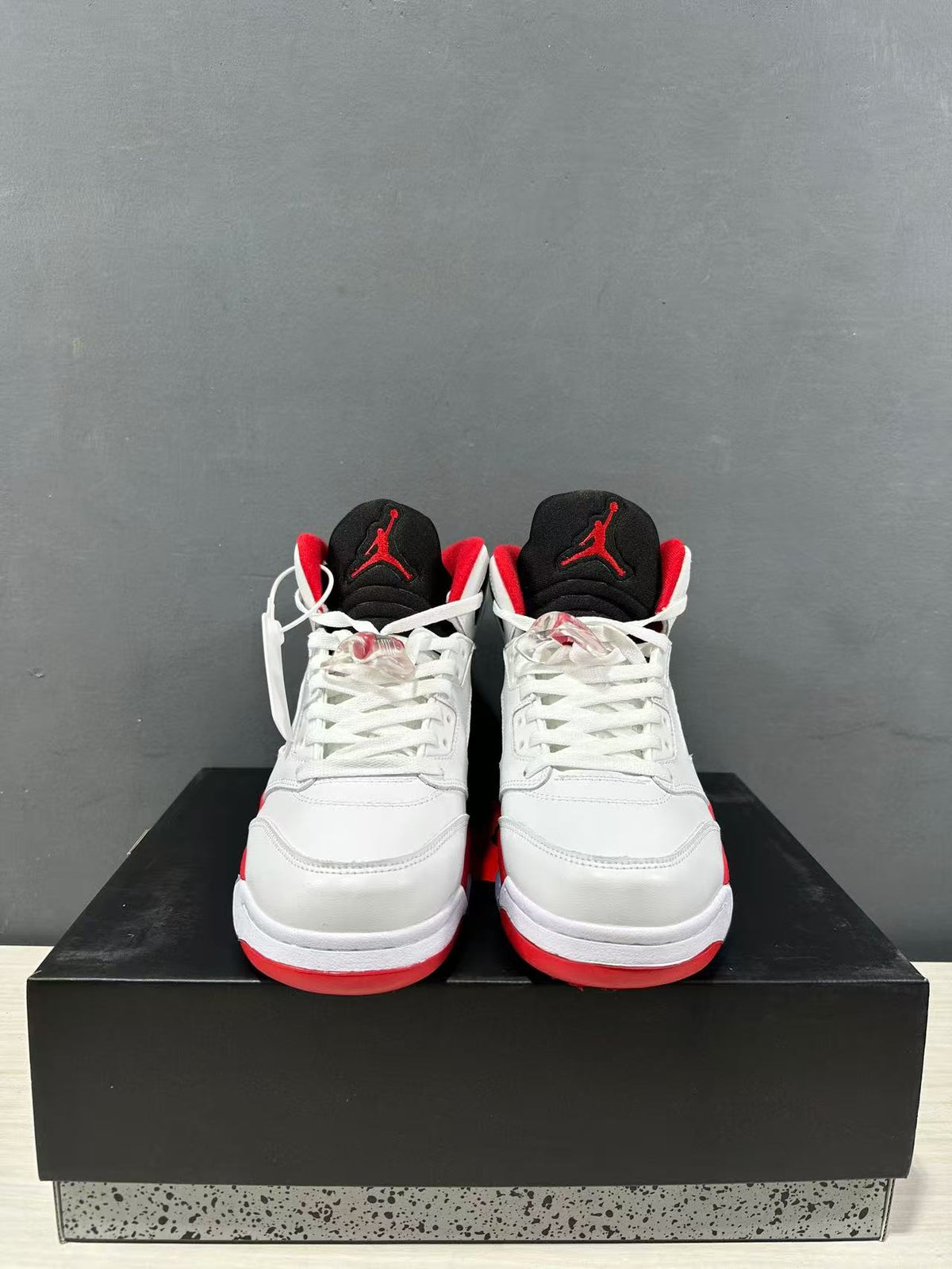 Front view of the pair showing white toe boxes, white laces, black tongues, and red tongue logos.