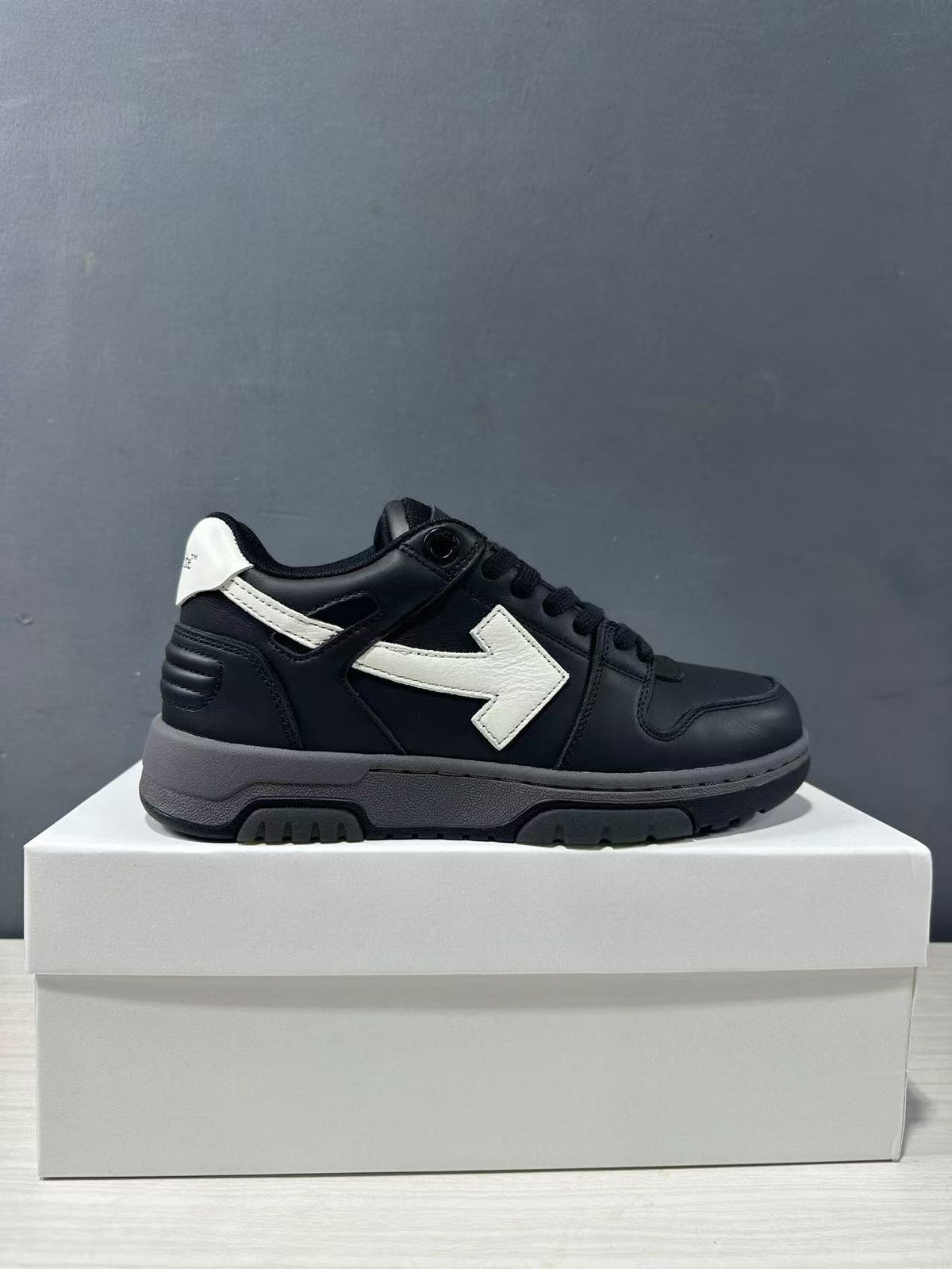 Single side-profile view of the black and white low-top sneaker on a white box.