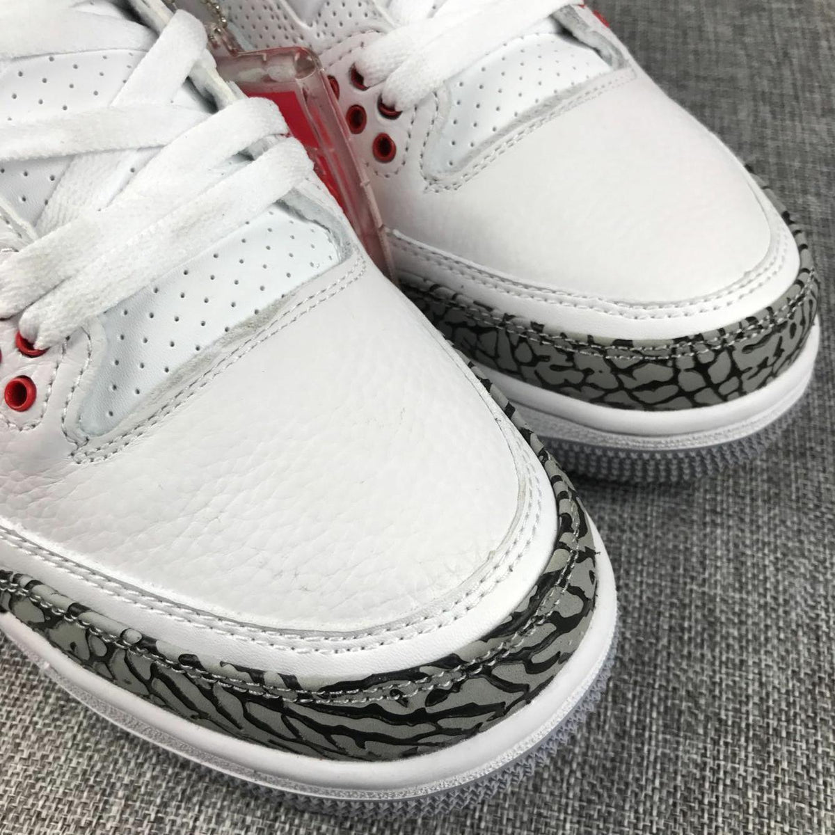 Close-up of the white textured toe boxes, stitching, and grey-and-black elephant-print toe overlays.