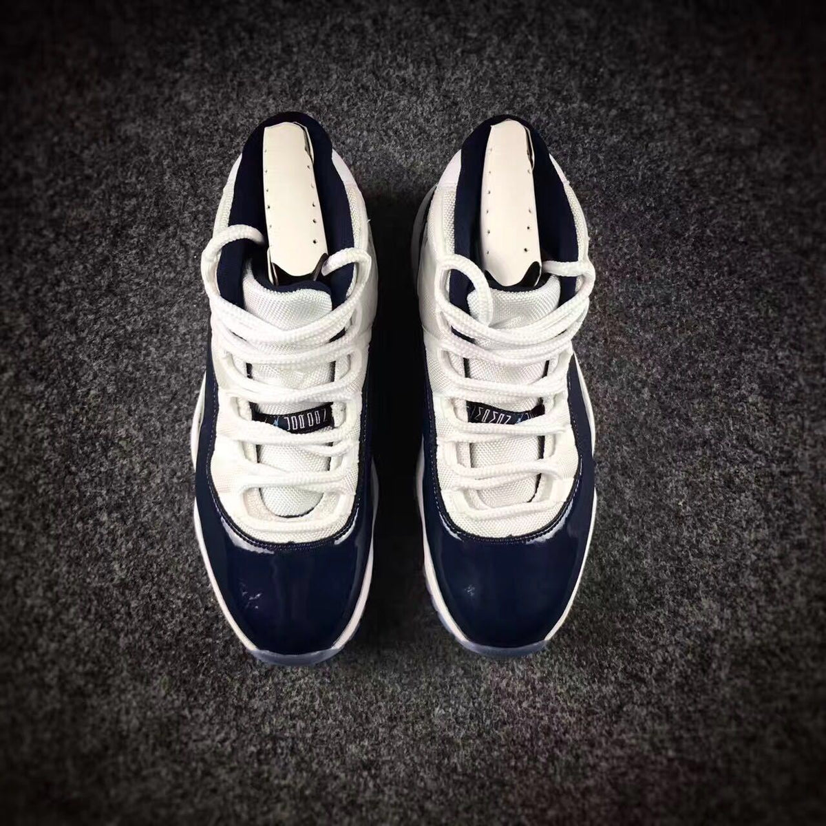 Top-down view of the pair showing the white laces, navy tongues, and glossy navy toe boxes.