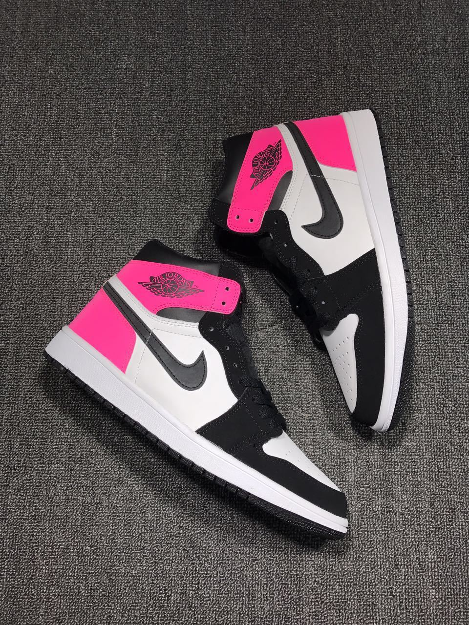 Pair of pink, black, and white high-top sneakers arranged diagonally on a textured surface.