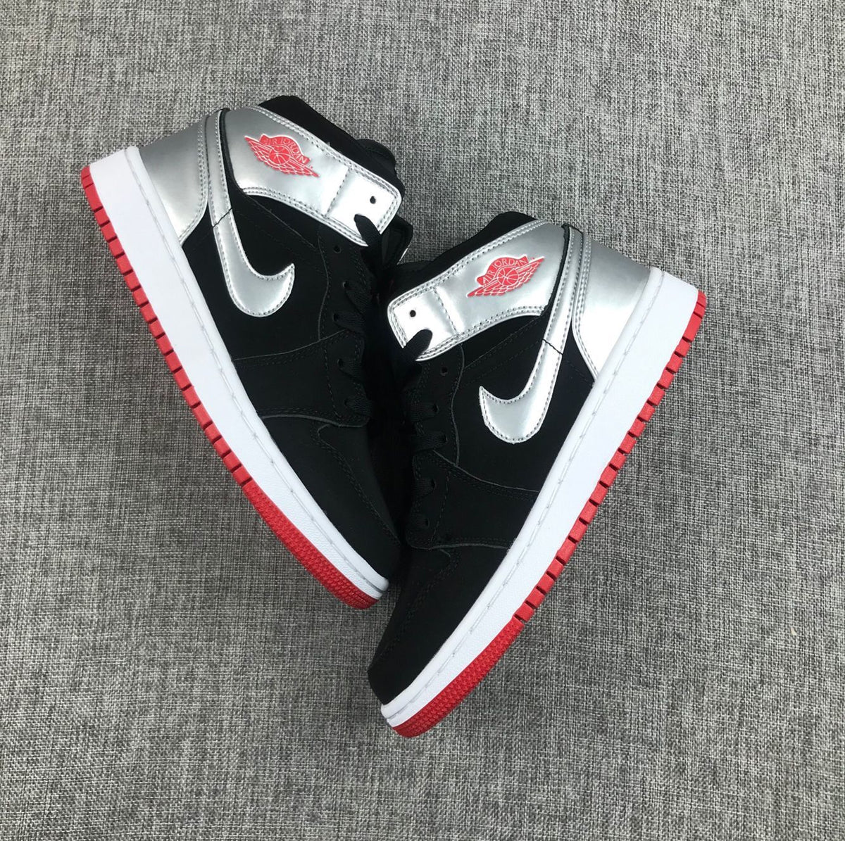 Top-down view of the pair highlighting the silver overlays, black uppers and red outsoles.