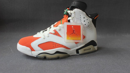 Three-quarter side view of one sneaker highlighting the orange toe, white overlays, black accents, and hangtag.
