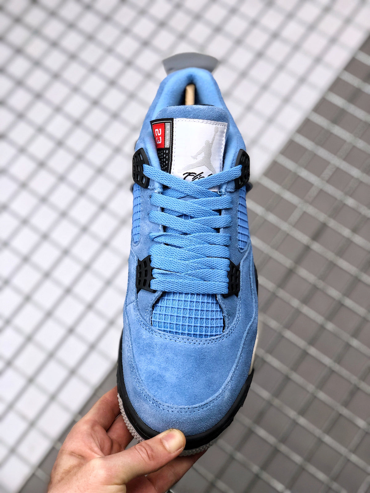 Top view of the blue Air Jordan 4 sneaker showing the tongue label, lacing, and forefoot.