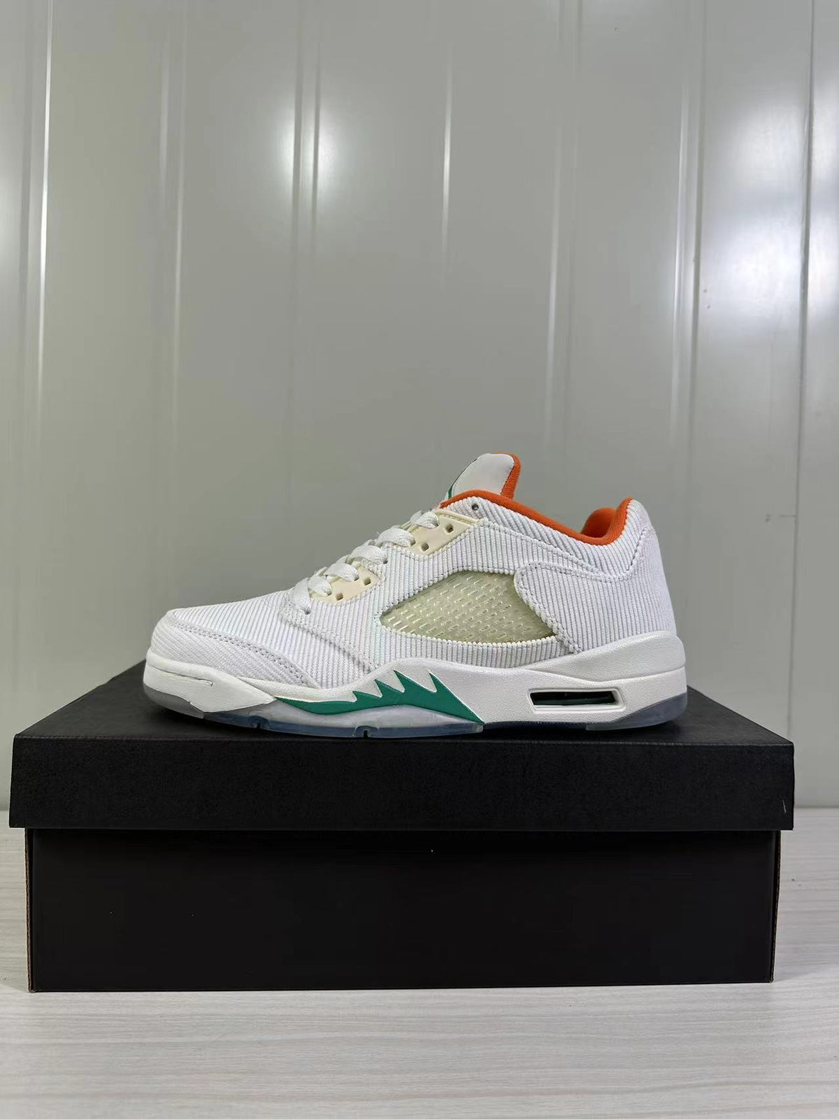 Side profile of a white low-top sneaker showing the green jagged midsole accent and visible air-window detail.