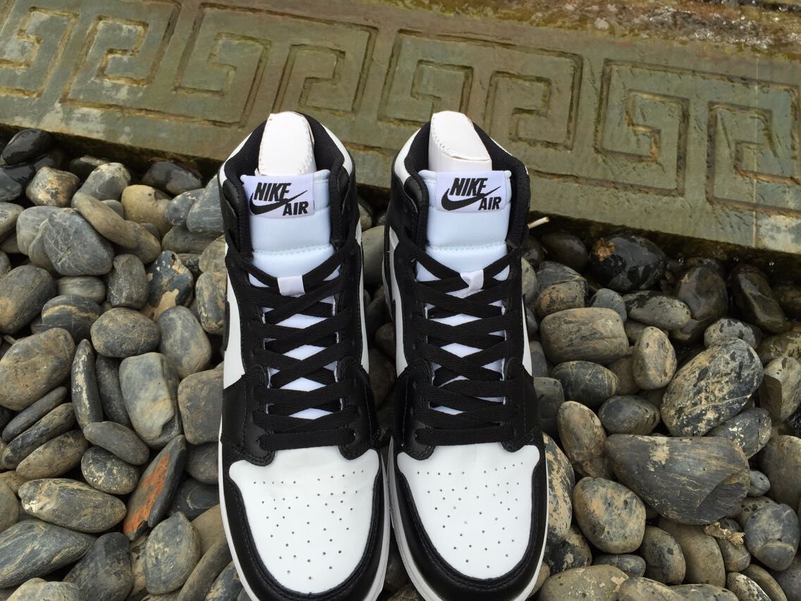 Front-facing view of the pair showing the white toe boxes, black overlays, tongue labels, and high-top shape.