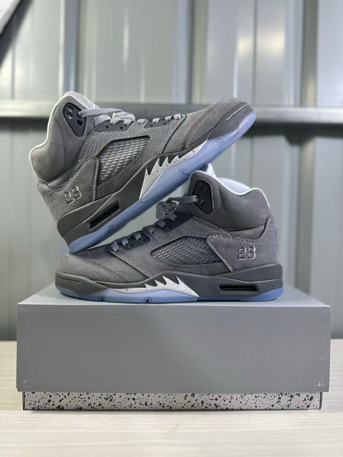 Two grey high-top sneakers displayed together, showing their side panels, lace areas, black midsoles, and translucent blue outsoles.