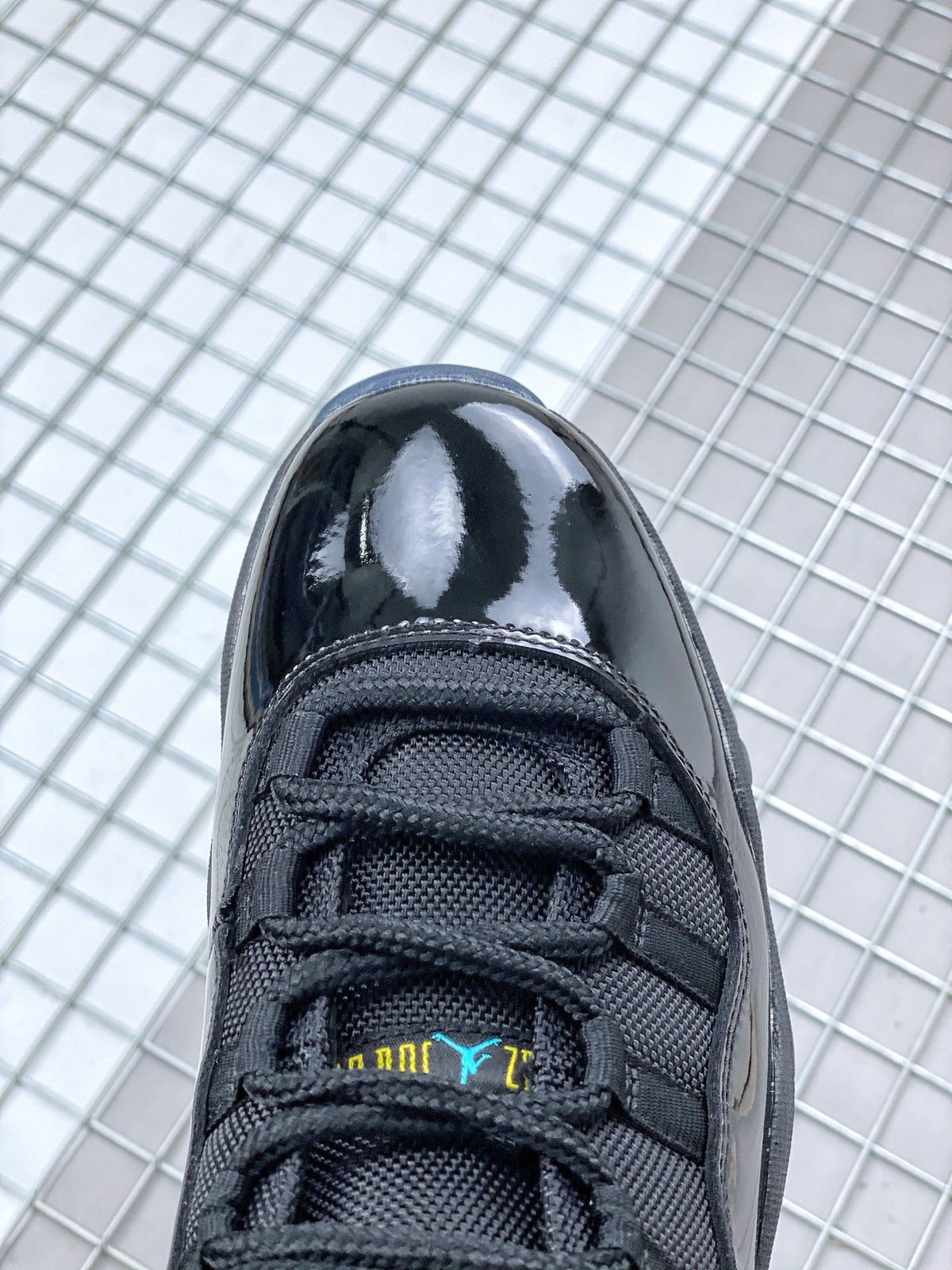 Close-up of the black sneaker toe box, black laces and tongue with blue and yellow branding details.