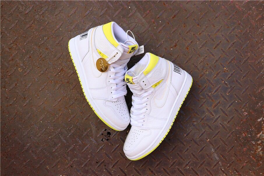 Overhead view of the paired white and yellow sneakers with a round hanging tag.