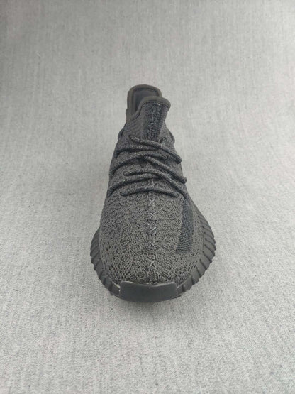 Front view of a black knit sneaker with black laces and a rounded toe.