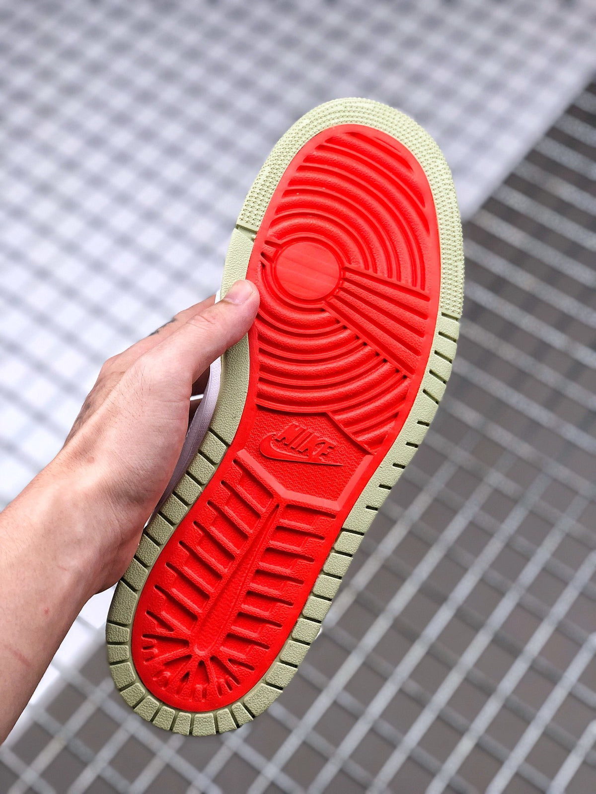 Bottom view of the sneaker showing the red traction area and olive green perimeter of the outsole.