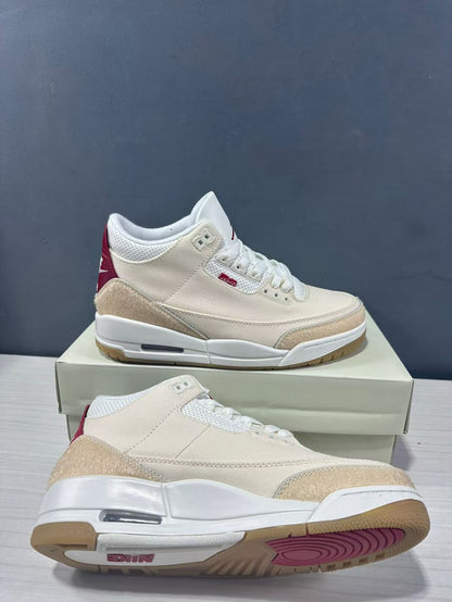 Angled view of the cream and red Air Jordan 3 Retro sneakers showing the white midsole, visible air window, and gum outsole.