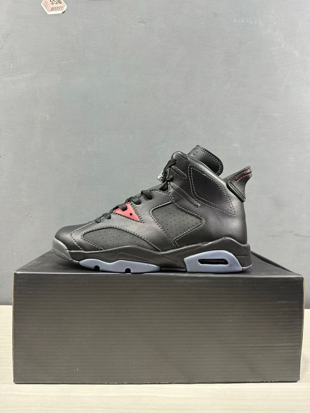 Side profile of the black mid-top sneaker with perforated panels and gray outsole details.
