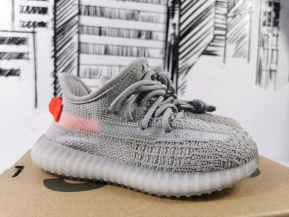 Side view showing the gray upper, pink side stripe, orange heel accent, and translucent sole.