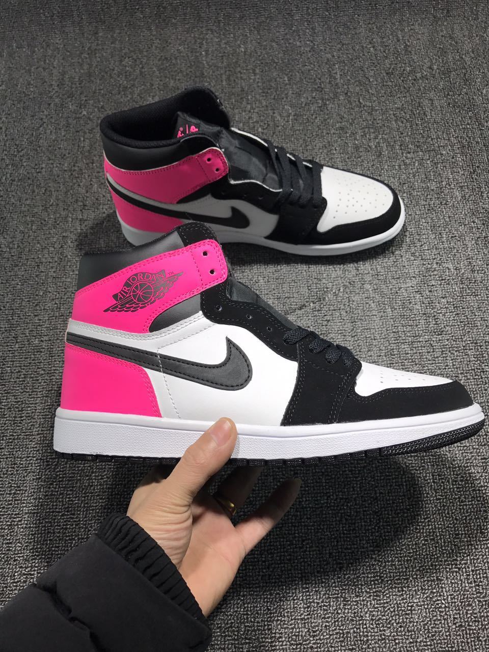 Side view of the high-top sneaker with pink collar and heel accents, black overlays, white panels, and a dark swoosh-shaped side mark.