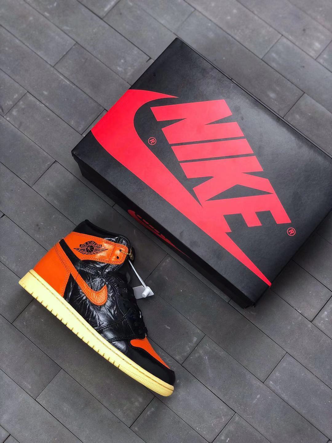 Sneaker and shoebox displayed together, with black and orange color blocking visible on the shoe.
