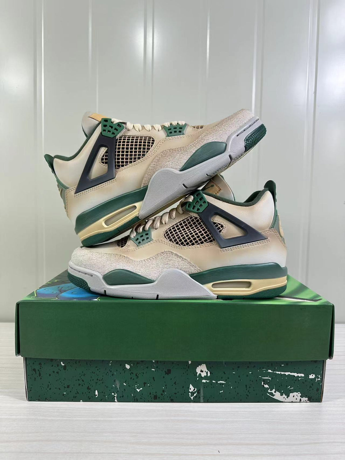 Stacked side view of the off-white and dark green Air Jordan 4 Retro sneakers.