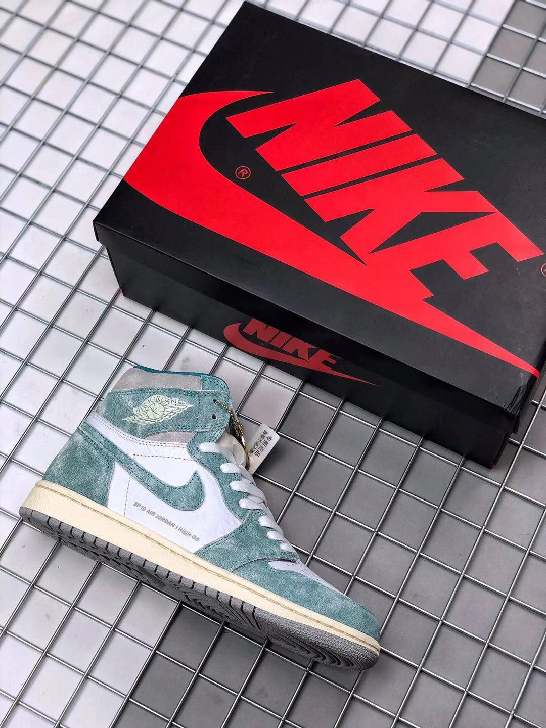 Air Jordan 1 high-top sneaker beside a black and red shoebox, showing the teal-green and white color scheme.