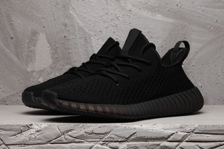 Front three-quarter view of a black lace-up sneaker with a textured upper and rounded toe.