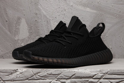 Front three-quarter view of a black lace-up sneaker with a textured upper and rounded toe.
