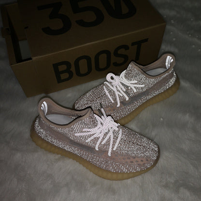 Flash-lit view of taupe-pink sneakers showing reflective details, with a box marked 350 BOOST in the background.